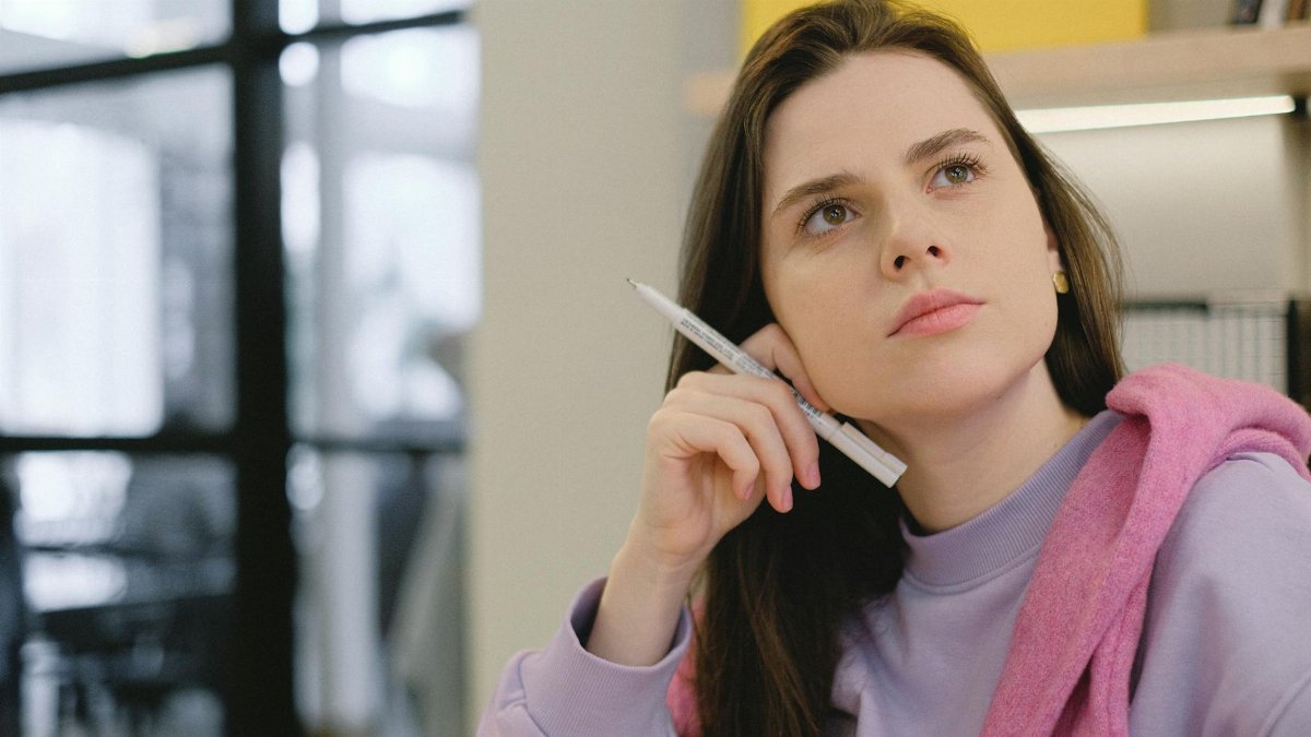A young woman with long dark hair, pensively studying indoors. Calm and focused atmosphere.