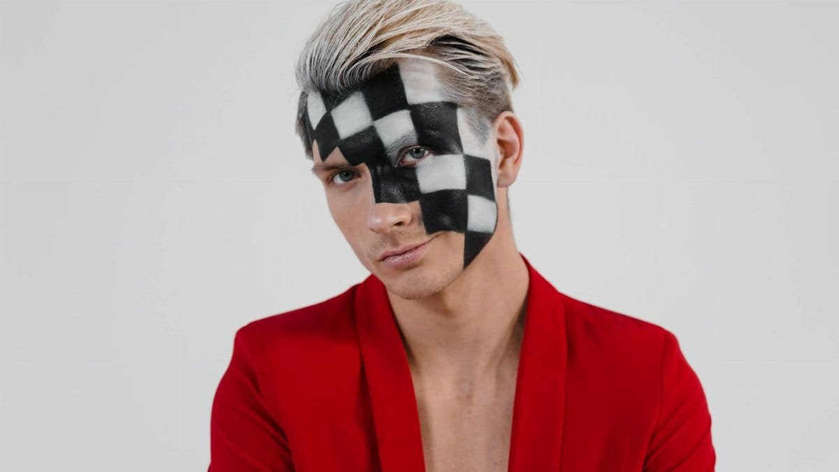 A unique portrait depicting a person with checkerboard face paint in a red jacket.
