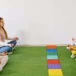 Kids and teachers in a preschool yoga session practicing mindfulness indoors.