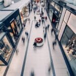 A vibrant scene capturing a busy shopping mall with modern stores and diverse shoppers on the move.