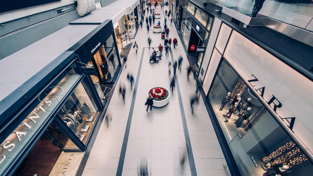 A vibrant scene capturing a busy shopping mall with modern stores and diverse shoppers on the move.