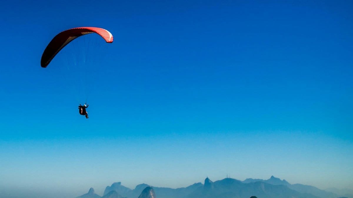 A paraglider flies high above a picturesque mountain range, showcasing freedom and adventure.