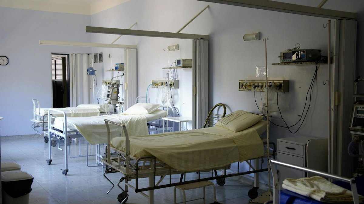 Spacious hospital room with several empty beds and medical equipment, emphasizing healthcare and hygiene.
