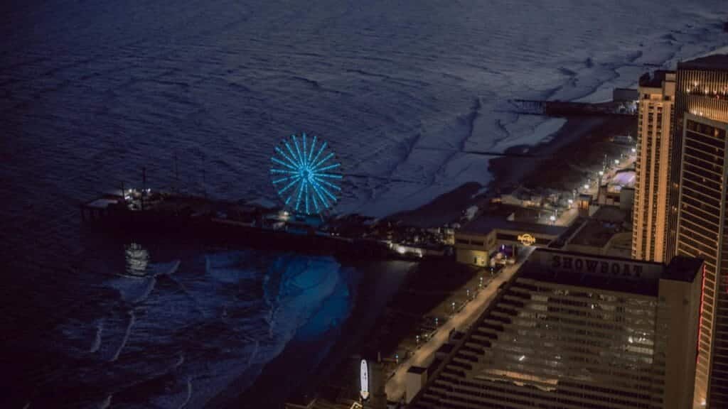 Stunning aerial view of Atlantic City at night featuring an illuminated Ferris wheel by the coast.