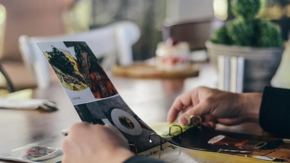 A person looking through a restaurant menu indoors, showcasing food selection.
