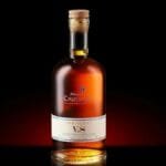 A bottle of Armagnac VS with a cork, elegantly displayed against a dark background.