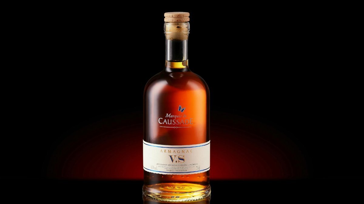 A bottle of Armagnac VS with a cork, elegantly displayed against a dark background.
