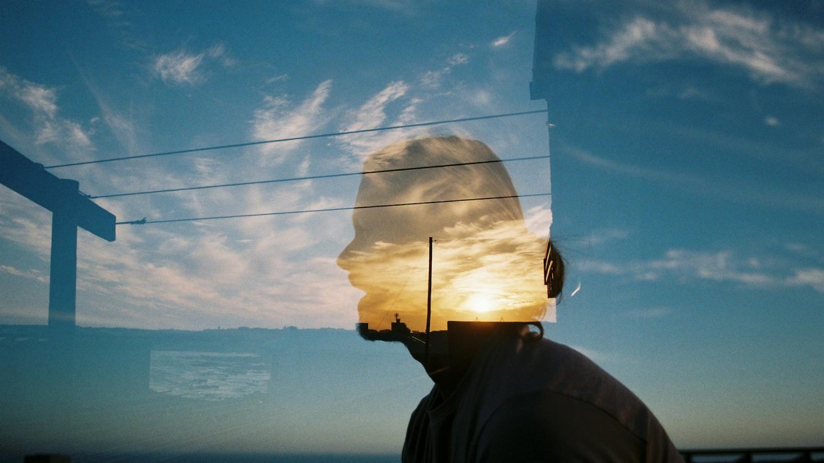 Artistic double exposure of a silhouette with a scenic sky background, blending nature and human form.