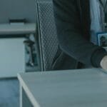 Close-up of a man working in a modern office setting, wearing an ID badge.