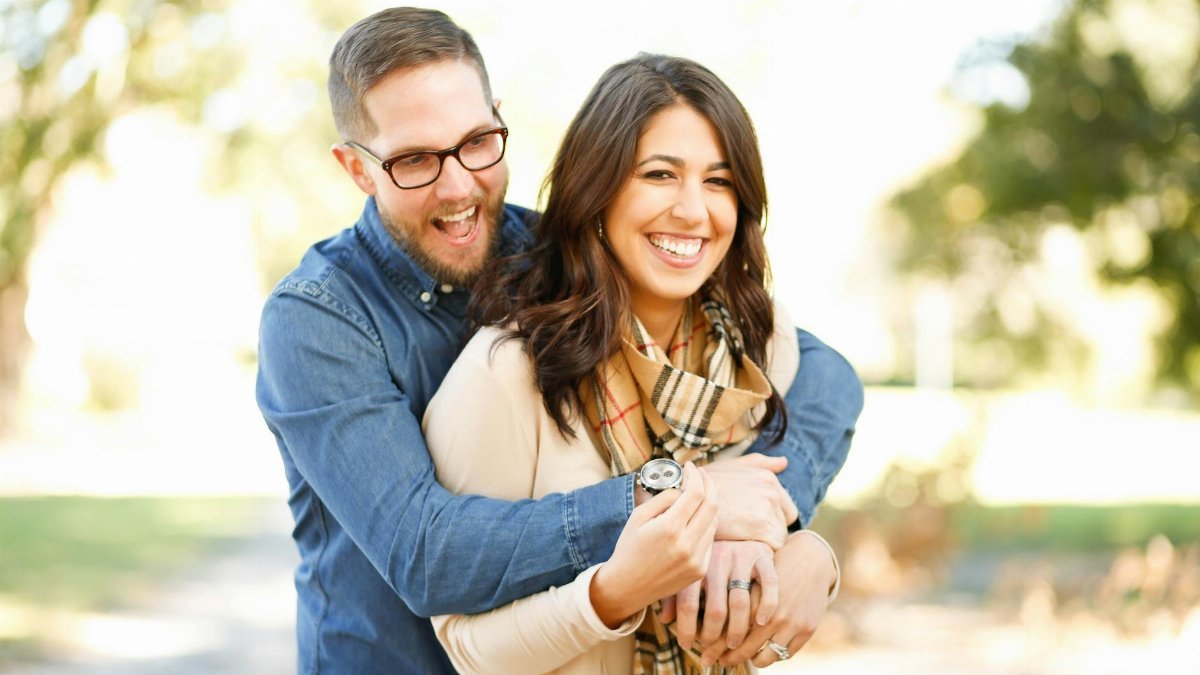 A happy couple enjoying an outdoor engagement photoshoot with laughter and love.