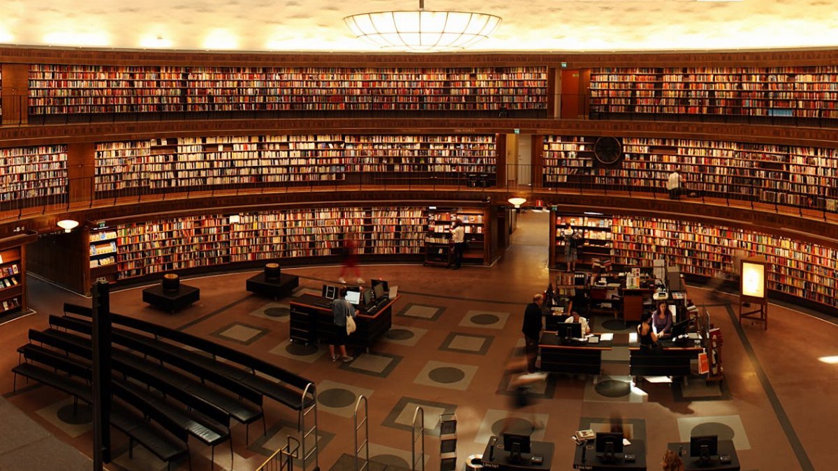Panoramic view of a grand circular library with shelves full of books and study desks.