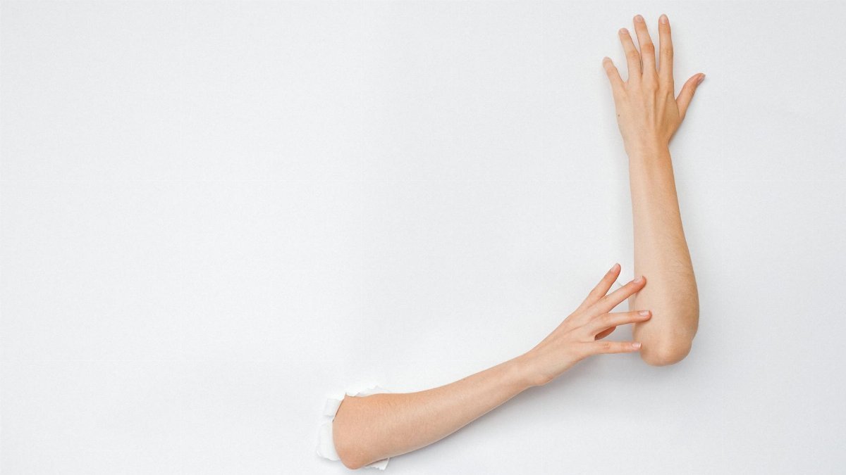A creative and artistic image of hands extending from a hole in a white wall, highlighting human expression.