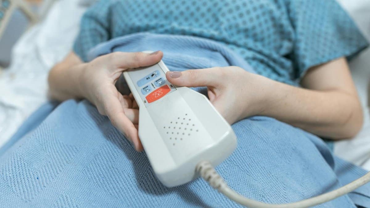 Close-up of a patient's hands holding a remote control in a hospital bed, showing care and medical settings.