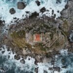 Stunning aerial shot of a coastal cliff in Montenegro, featuring rocky terrain and crashing waves.