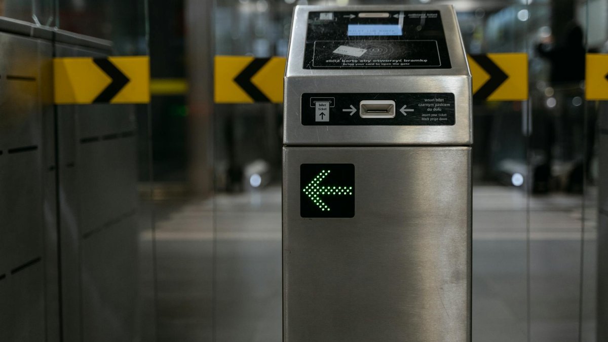A modern ticket gate with an illuminated arrow for access control in transit systems.