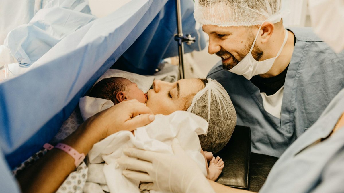A cherished family moment as new parents welcome their baby in a hospital delivery room.
