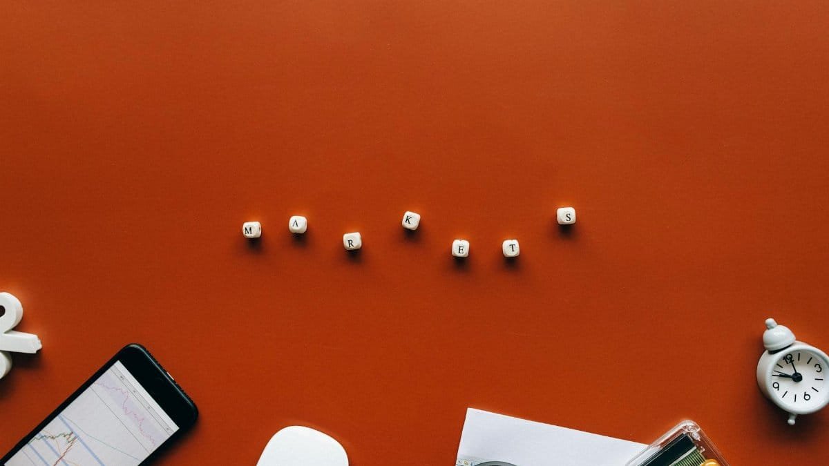 Creative still life with financial tools and the word 'MARKETS' on an orange background.