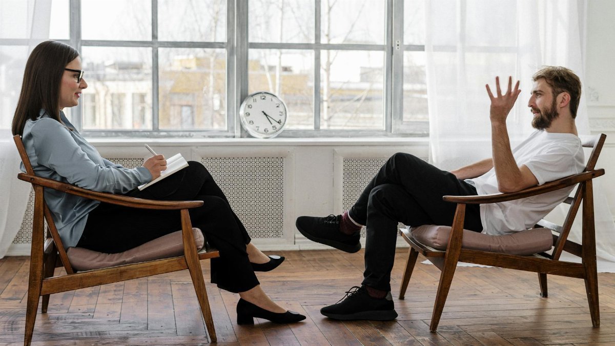A therapist engaging in a counseling session with a male patient to support mental health.