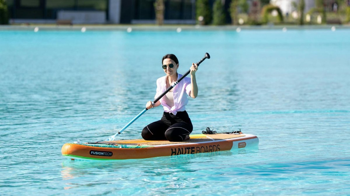 Adult woman enjoying a sunny day paddleboarding on a pool in Kahramanmaraş, Türkiye.