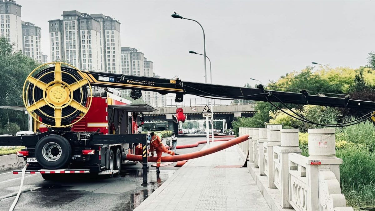 Flood management team operating machinery in urban area for water drainage.