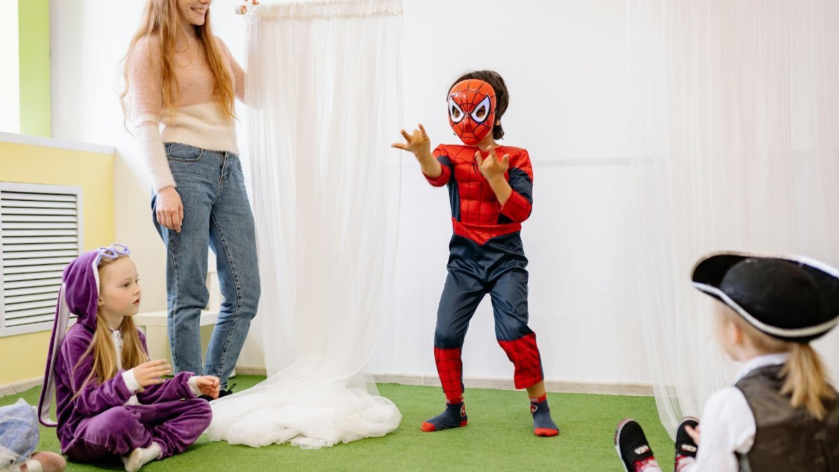 Children dressed up as superheroes playing in a joyful preschool setting indoors, promoting creativity and fun.
