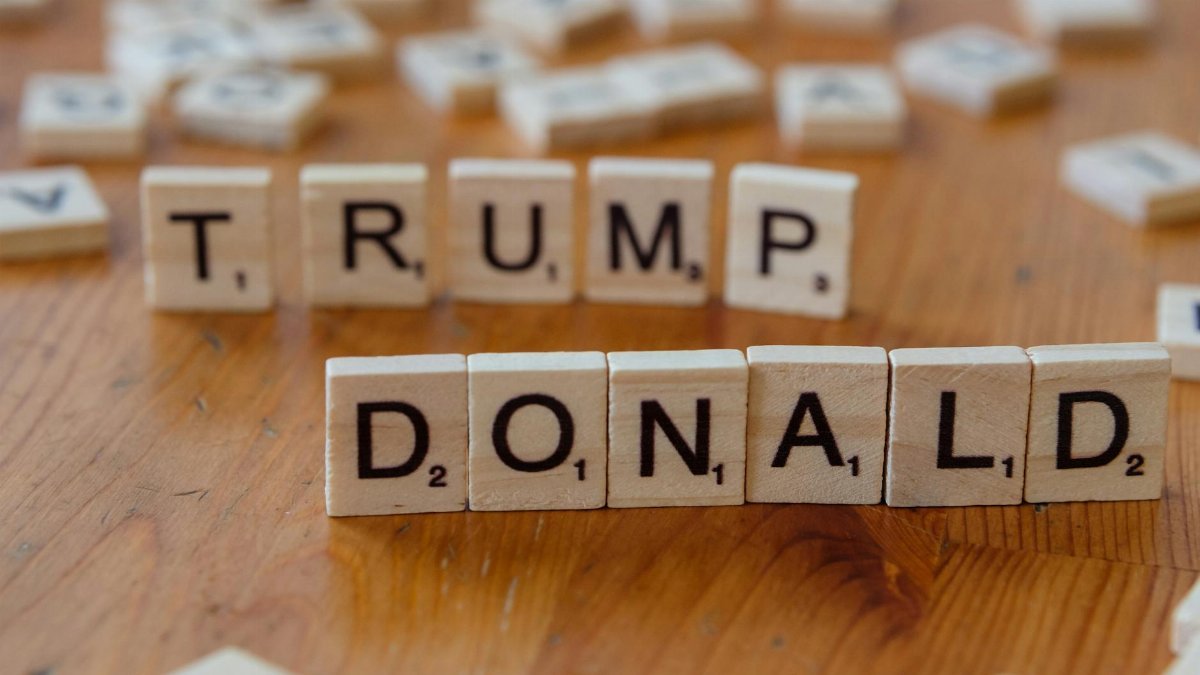 Close-up of Scrabble tiles spelling 'Donald Trump' on a wooden table.
