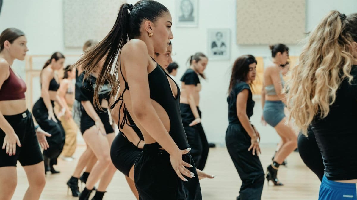Group of women engaging in an energetic dance class inside a bright, modern studio.