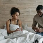A supportive couple sitting in bed, comforting each other during illness indoors.