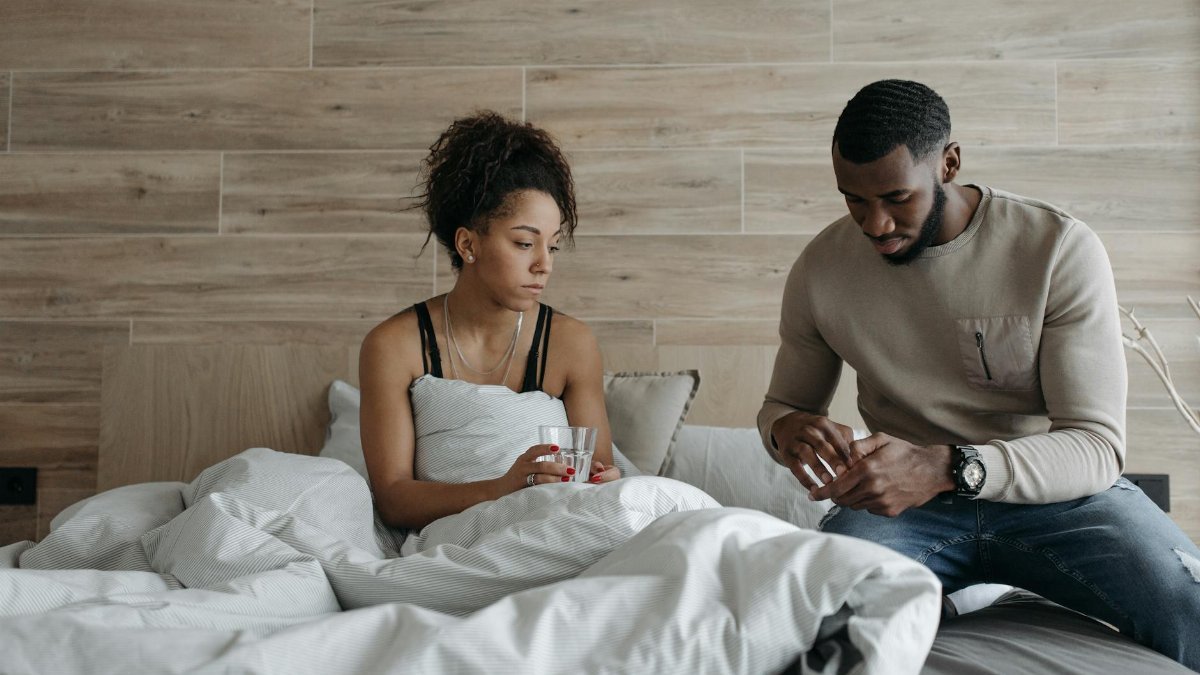 A supportive couple sitting in bed, comforting each other during illness indoors.
