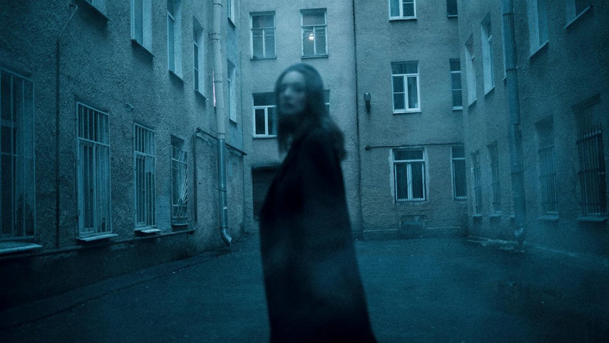 Eerie urban courtyard with blurred figure creating a mysterious atmosphere.