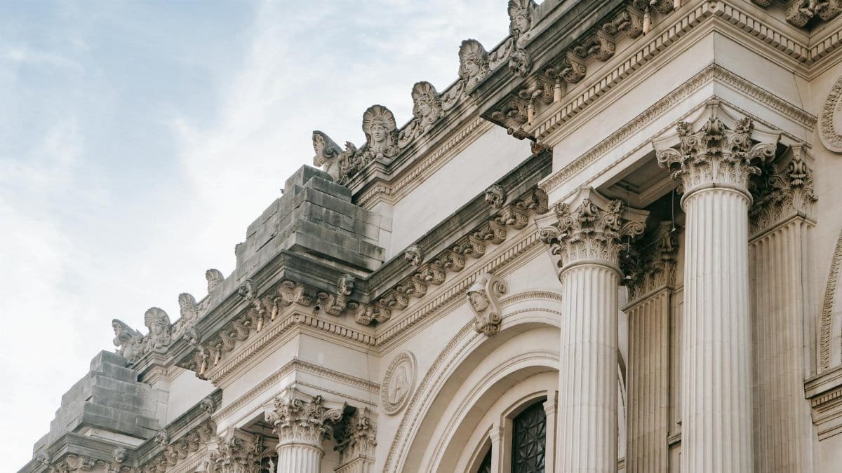 Exterior of aged stone building with classic architecture of facade with columns and ornamental elements