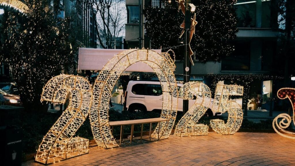 Illuminated 2025 sign on city street with decorative lights creating a festive atmosphere.