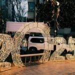 Illuminated 2025 sign on city street with decorative lights creating a festive atmosphere.