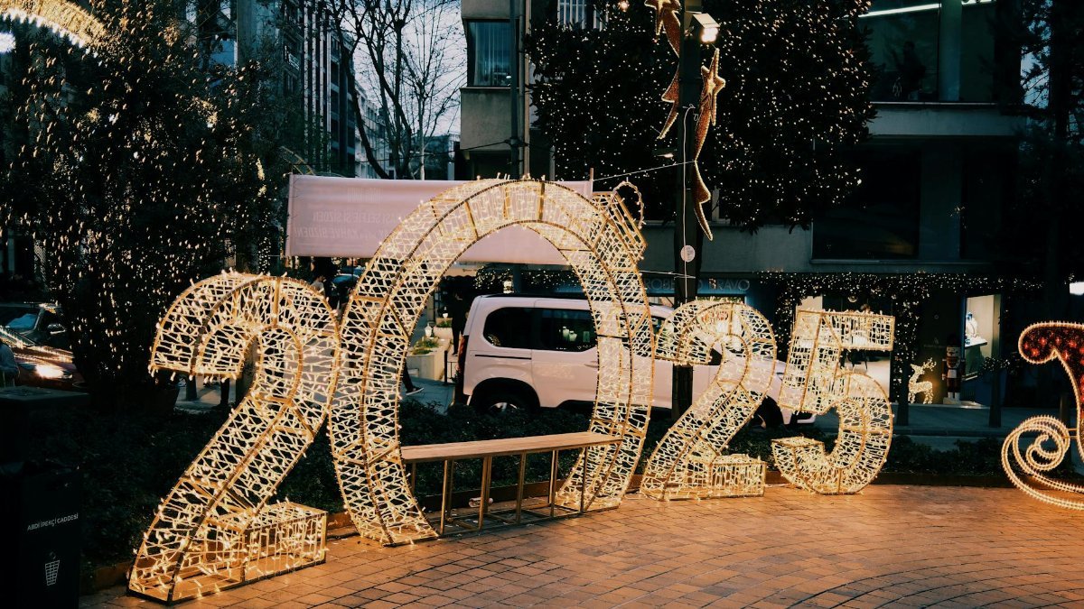 Illuminated 2025 sign on city street with decorative lights creating a festive atmosphere.