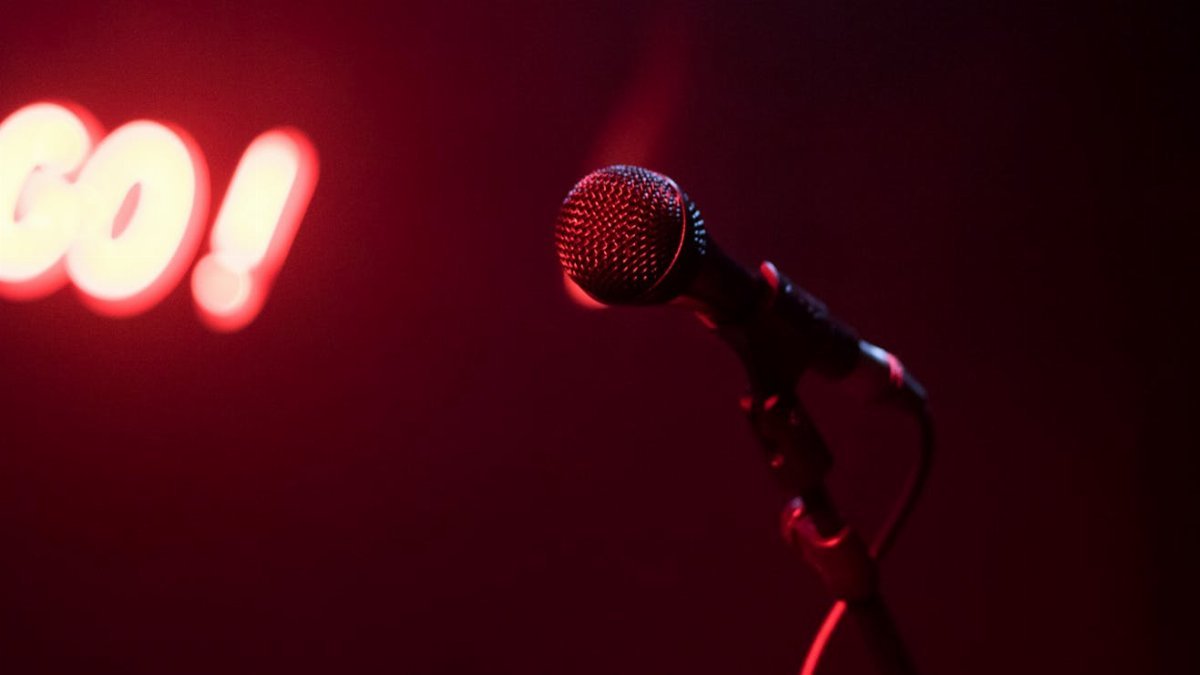 Microphone on stage with glowing red 'GO!' sign, perfect for nightlife themes.