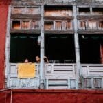 Children looking out of a rustic window with colorful walls in Lahore, capturing daily life.