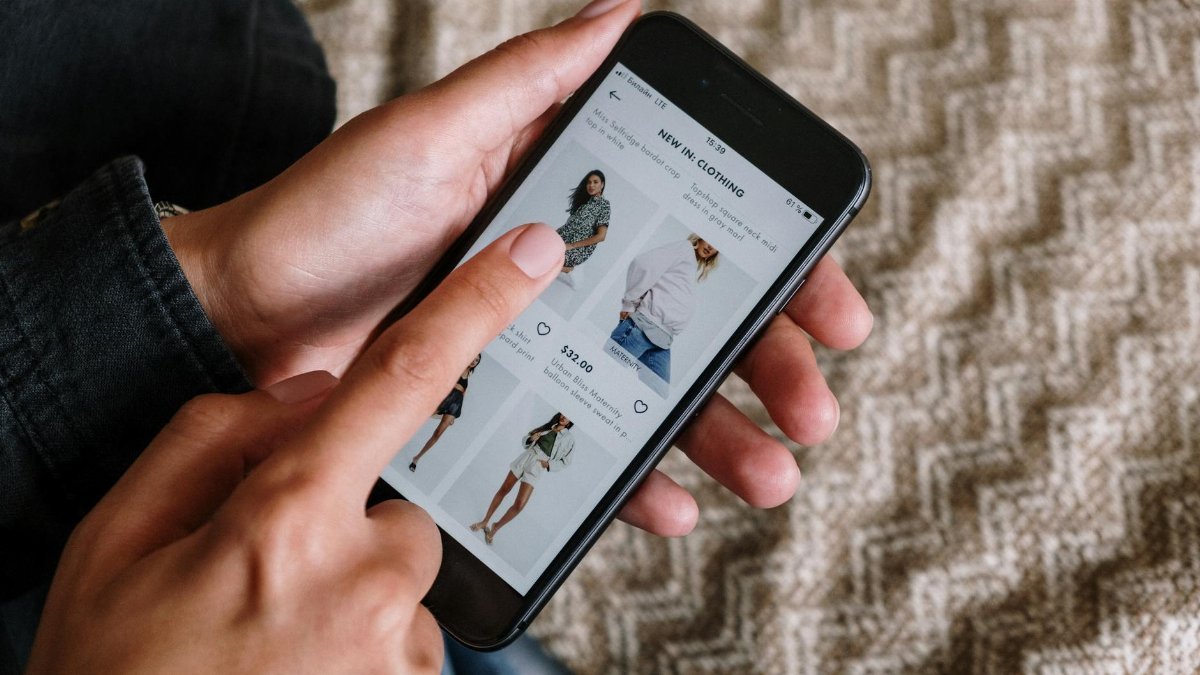 Person browsing clothing items on a smartphone, showcasing modern online shopping experience.