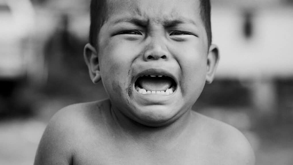 Heartfelt portrait of a young child crying, showcasing raw emotion in black and white.