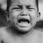 Heartfelt portrait of a young child crying, showcasing raw emotion in black and white.