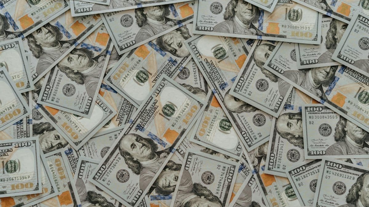 US hundred dollar bills scattered in abundance creating a financial backdrop.