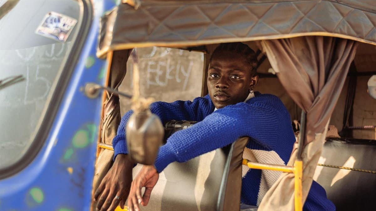 Young man in a colorful keke, Lagos, Nigeria, showcasing urban life and style.