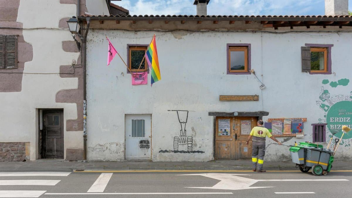 A street cleaner stands by a building with rainbow and pink flags in Elizondo, Spain.