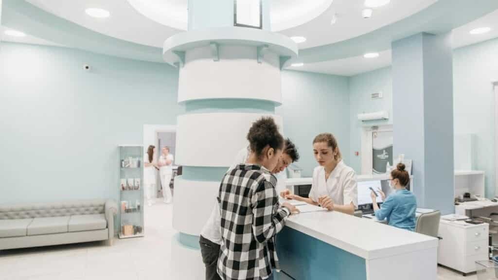 Bright, welcoming clinic reception with patients interacting with staff for registration.