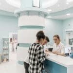 Bright, welcoming clinic reception with patients interacting with staff for registration.