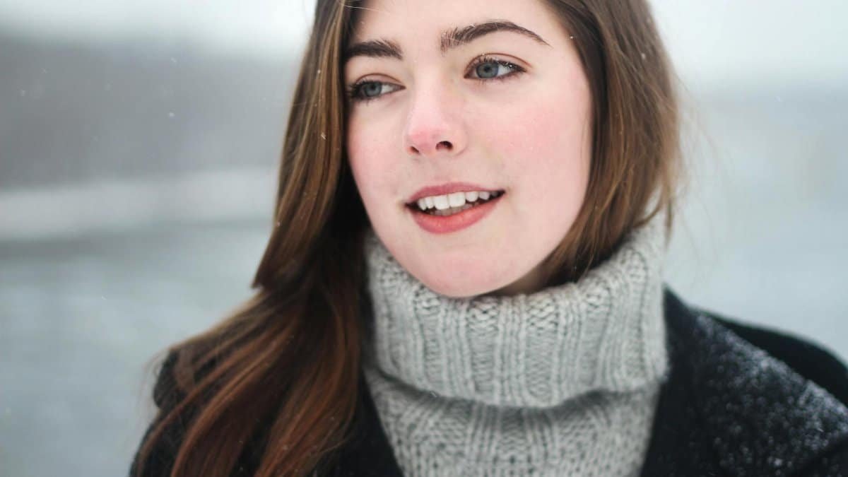Close-up portrait of a young woman smiling outdoors in the snowy winter.
