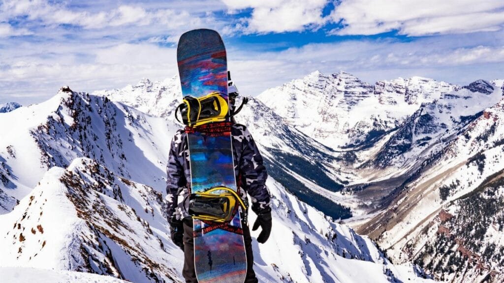 Snowboarder stands on snowy peak, gazing at breathtaking mountains in Breckenridge, Colorado.