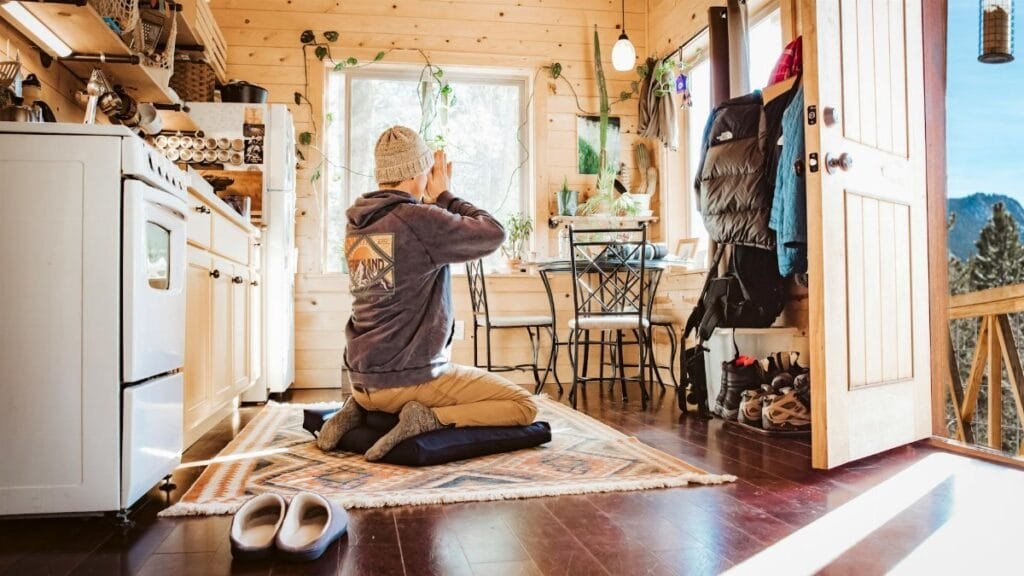 A person meditates in a cozy wooden cabin with mountain views in Colorado.
