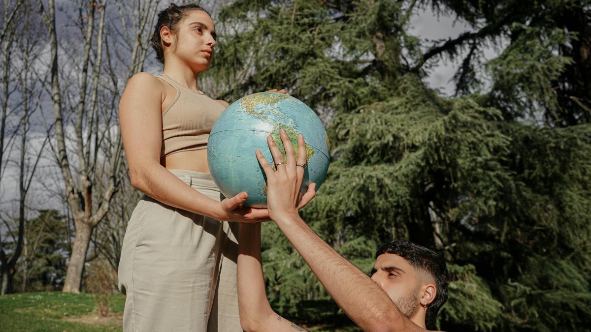 Two people holding a globe outdoors symbolizing environmental care.