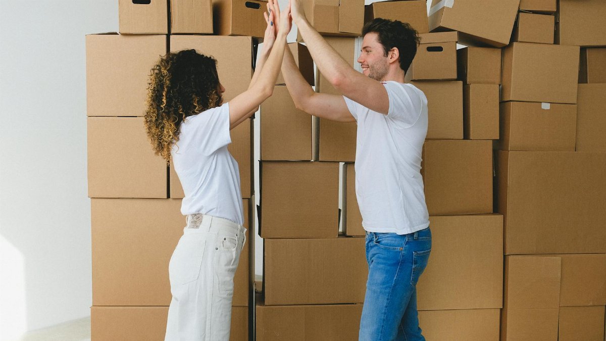 Joyful couple high-fiving in their new home surrounded by moving boxes.