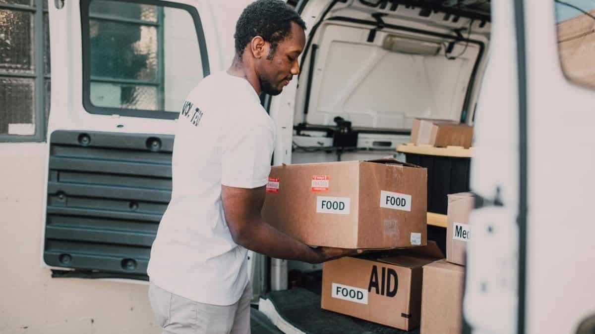 Volunteer worker loading food and aid supplies into a van for community distribution.
